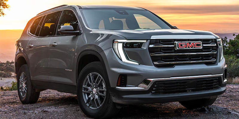 A silver suv parked up on a rock.