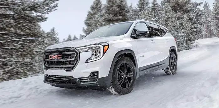a white gmc terrain driving in on an icy snowy road