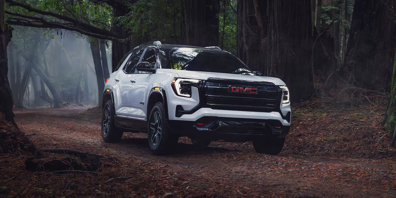 A white suv driving on a dirt road.