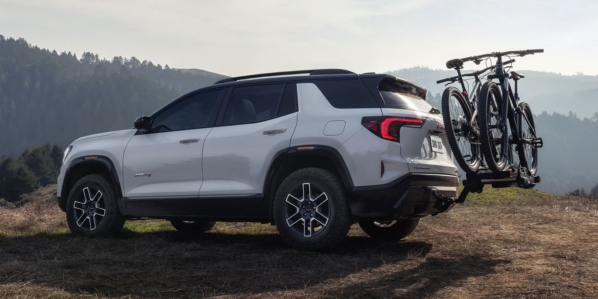 A white suv parked off-road with bikes on the back.