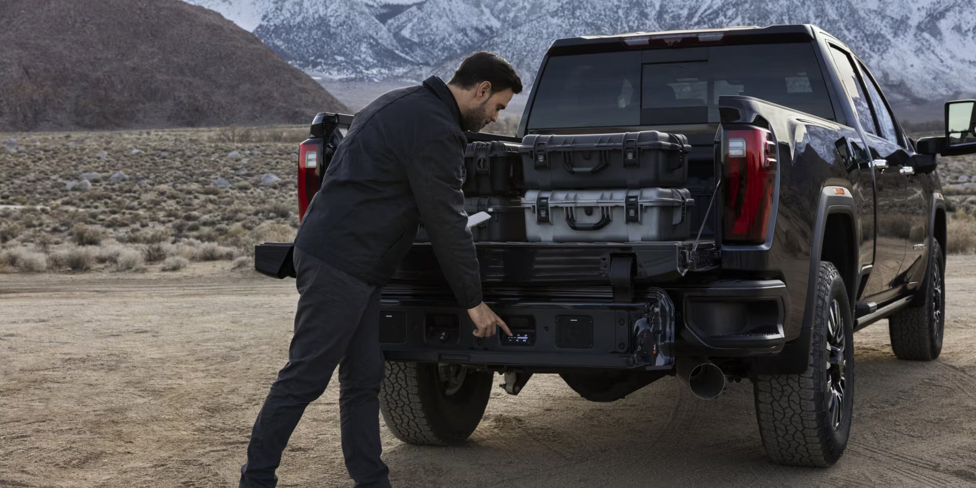 A man getting into the trunk of a black truck.